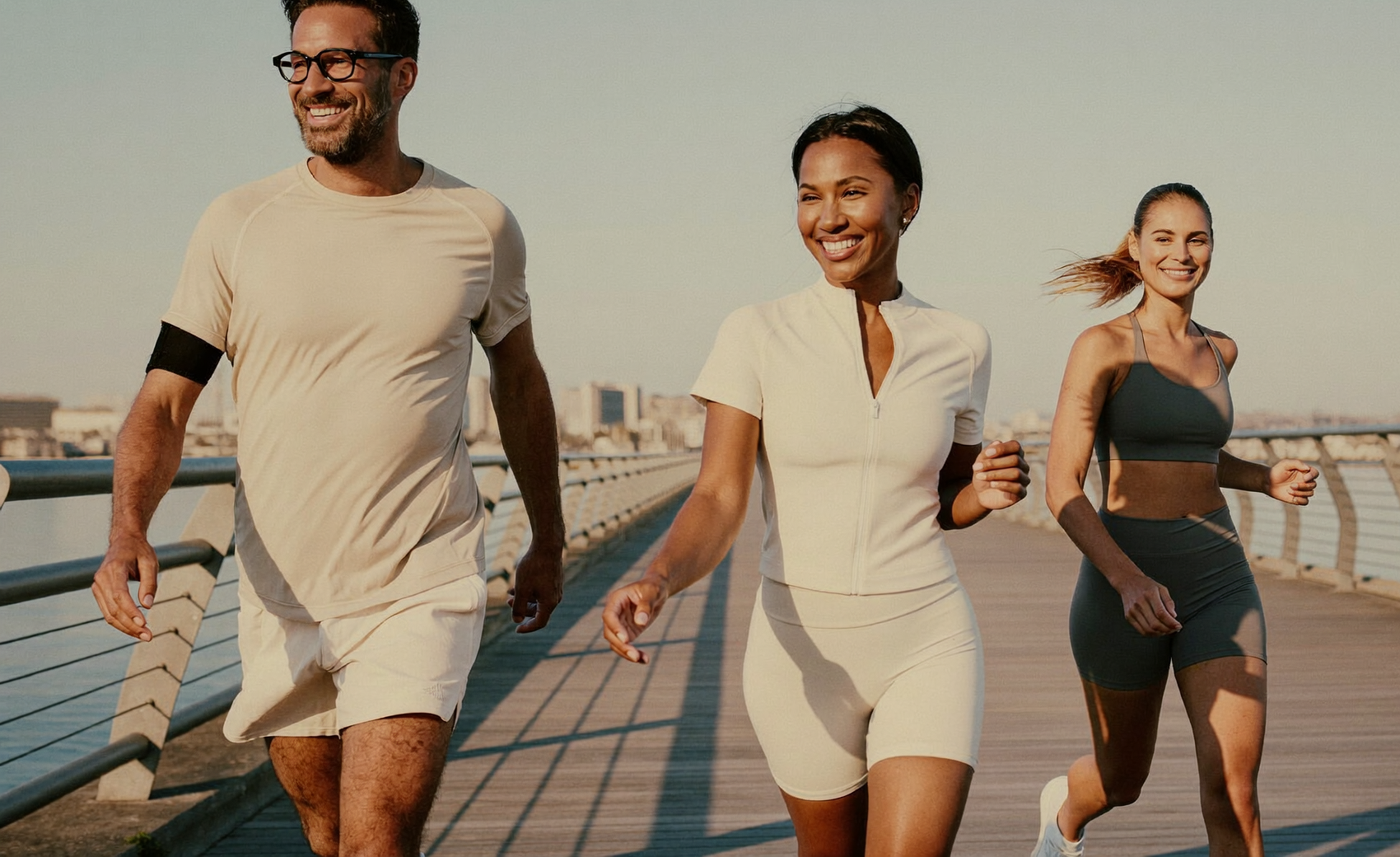 Three members power-walking together on a waterfront boardwalk at golden hour
