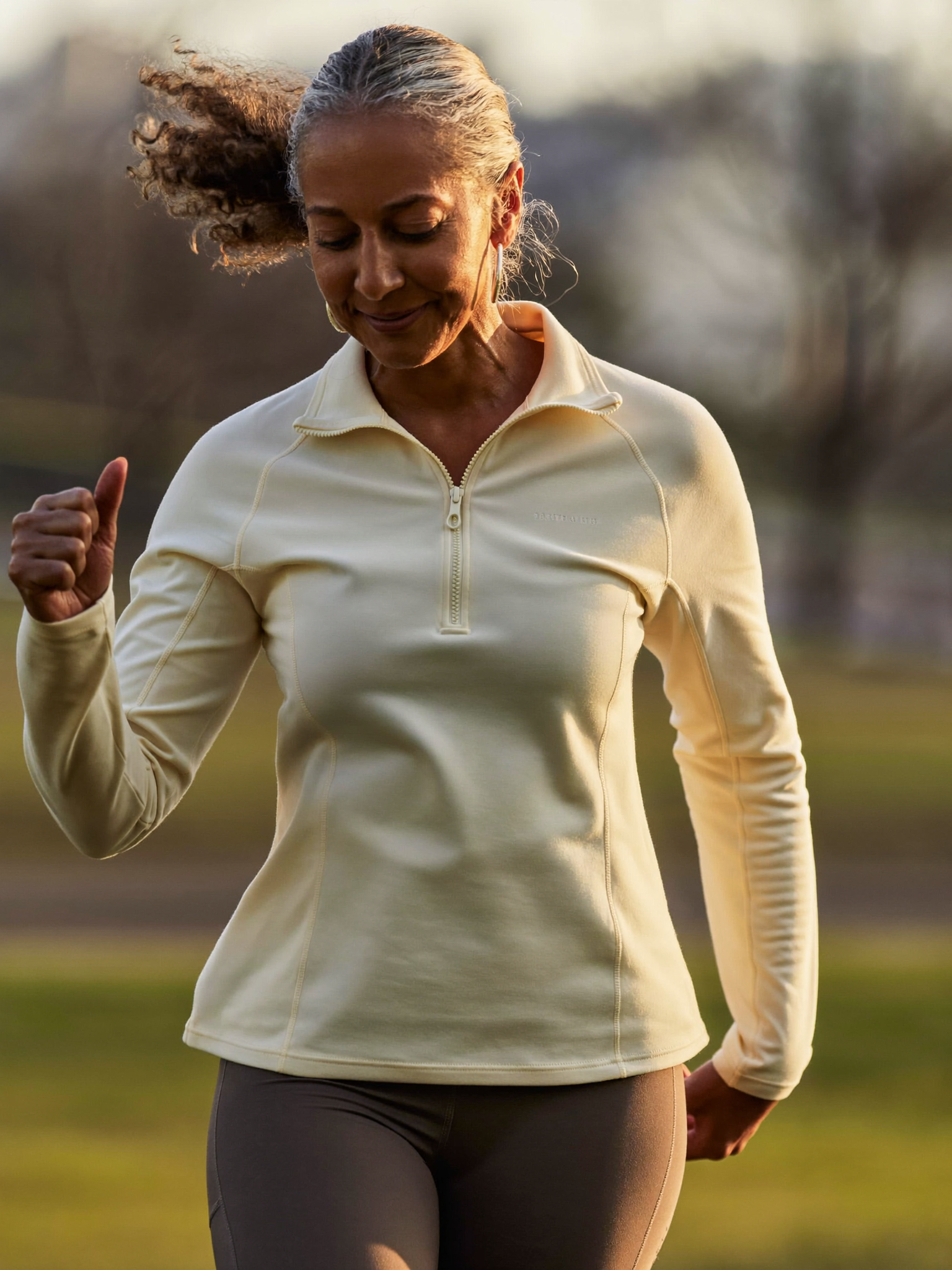 A woman in her fifties walking briskly at golden hour, focused and strong